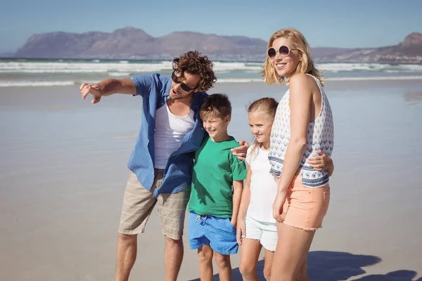 Hombre apuntando lejos con la familia en la playa — Foto de Stock