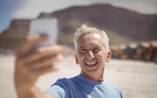 Старший чоловік бере селфі на пляжі — стокове фото