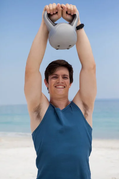 De hijs kettlebell man op strand — Stockfoto