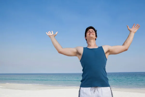 Hombre de pie en la playa con los brazos extendidos —  Fotos de Stock