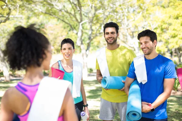 People with rolled exercise mats talking — Stock Photo, Image