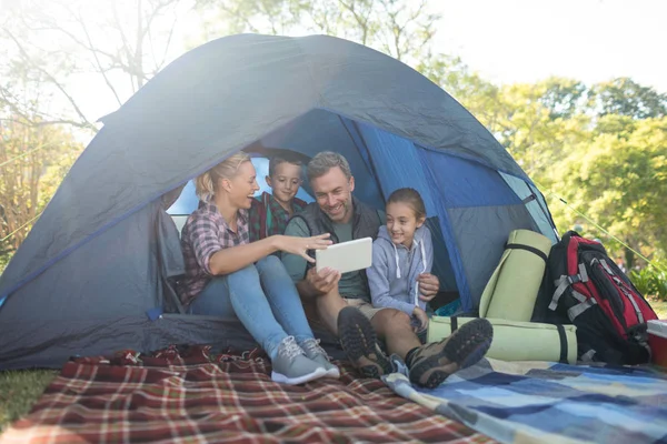 Семья смотрит на цифровой планшет в палатке — стоковое фото