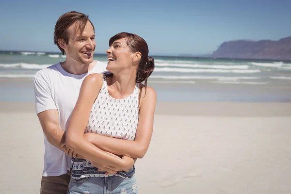 Fröhliches Paar umarmt sich am Strand — Stockfoto