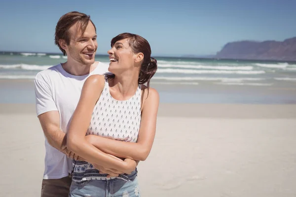 Vrolijke paar omarmen op strand — Stockfoto