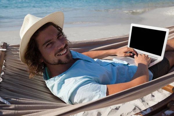 Homem usando laptop enquanto relaxa na rede — Fotografia de Stock