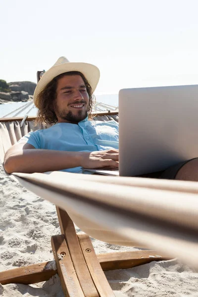 Człowiek za pomocą laptopa, relaksując się na hamaku — Zdjęcie stockowe