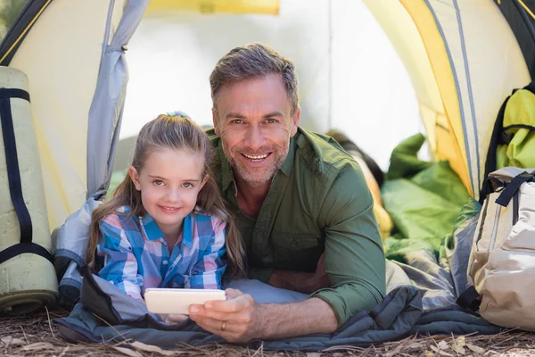 Father and daughter using phone in tent — Stock Photo, Image