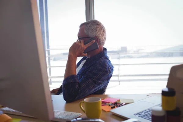 Businessman talking on mobile phone at office — Stock Photo, Image