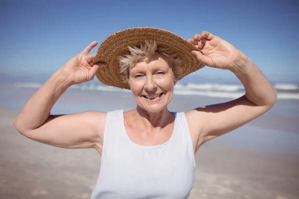 Mulher sênior usando chapéu de sol na praia — Fotografia de Stock