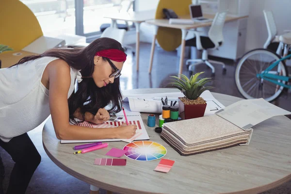 Empresaria trabajando mientras se apoya en el escritorio — Foto de Stock