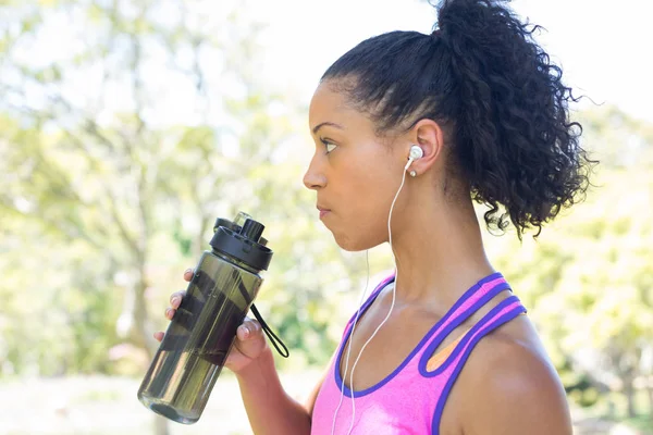 Kvinnliga joggaren dricksvatten i parken — Stockfoto