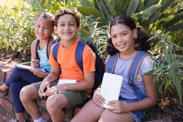 Amigos sosteniendo libros mientras están en el muro de contención — Foto de Stock