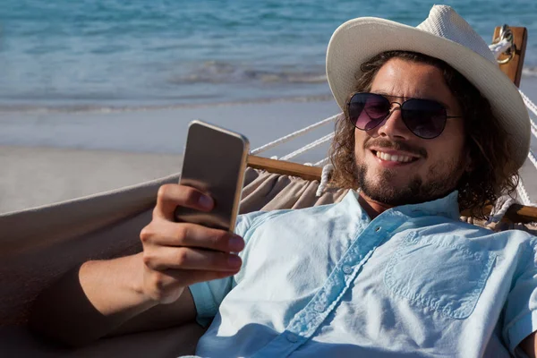 Hombre relajándose en la hamaca y usando el teléfono —  Fotos de Stock
