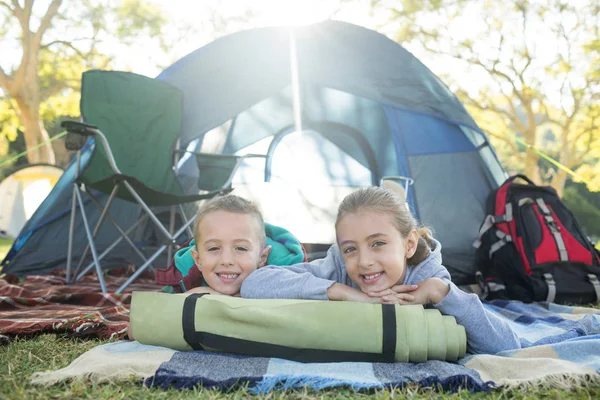 Frères et sœurs souriants couchés devant la tente — Photo