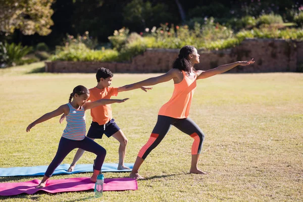 Entrenador con niños practicando Virabhadrasana II pose —  Fotos de Stock