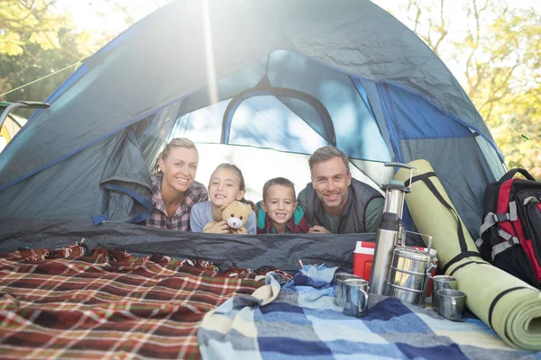 Família sorridente deitada na tenda — Fotografia de Stock