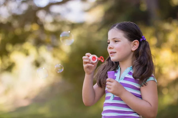 Flicka som leker med bubblan trollspö solig dag — Stockfoto