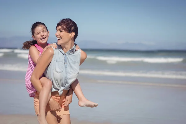 Madre piggybacking figlia in spiaggia — Foto Stock