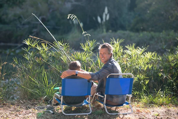 微笑着的父亲与儿子钓鱼阳光明媚的日子 — 图库照片