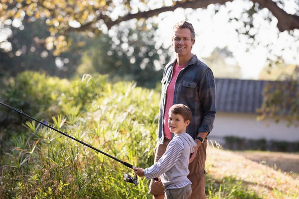 Far stod av pojke håller fiskespö — Stockfoto