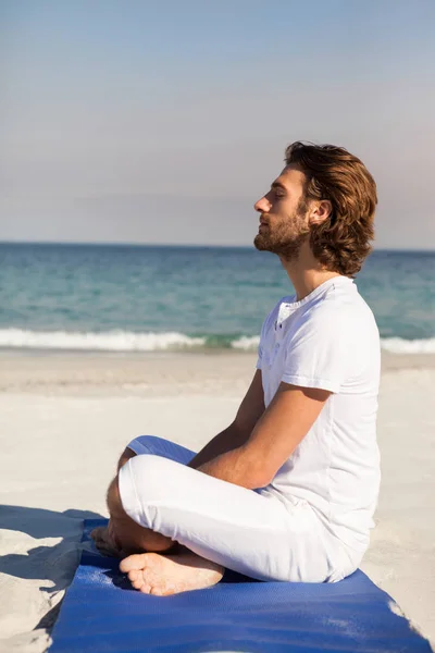 Man utför yoga på stranden — Stockfoto