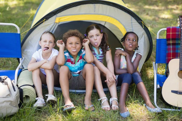 Barn gör ansiktet medan du sitter i tält — Stockfoto