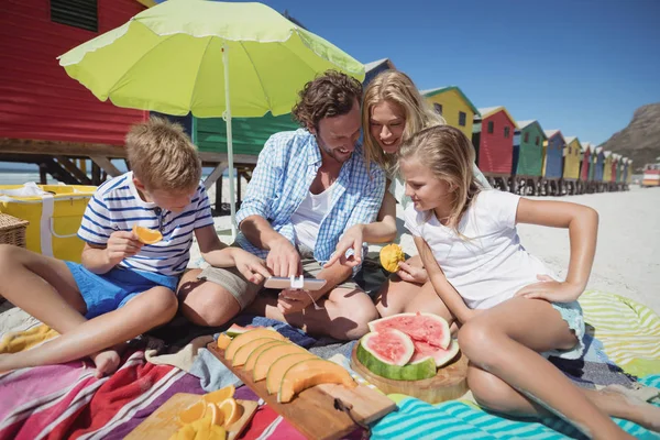 Familjen sitter tillsammans med frukter på filt — Stockfoto