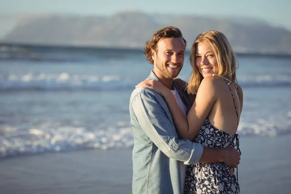 Улыбающаяся пара обнимается на пляже — стоковое фото