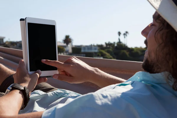 Hombre relajándose en la hamaca y usando la tableta —  Fotos de Stock