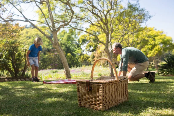 Padre e hijo extendiendo la manta de picnic — Foto de Stock