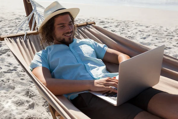 Man kopplar av på hängmattan och använder bärbar dator — Stockfoto