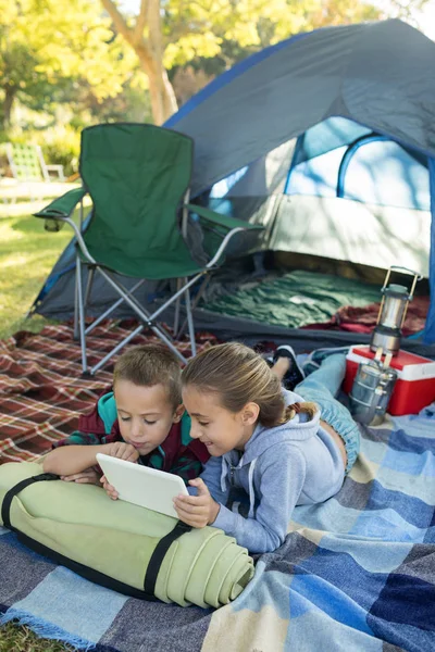 Siblings using laptop outside the tent — Stock Photo, Image