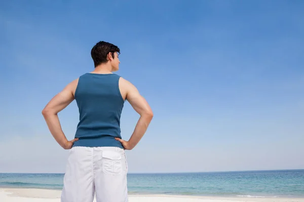 Muž, který stojí na pláži s rukou na boky — Stock fotografie