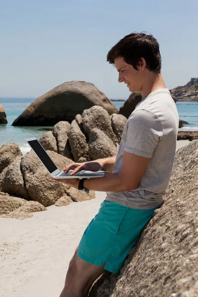 Mann lehnt sich an Felsen und benutzt Laptop — Stockfoto
