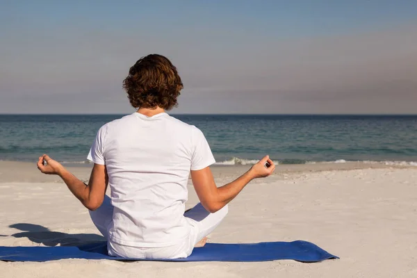 Man utför yoga på stranden — Stockfoto