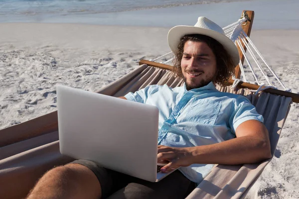 Homem usando laptop enquanto relaxa na rede — Fotografia de Stock