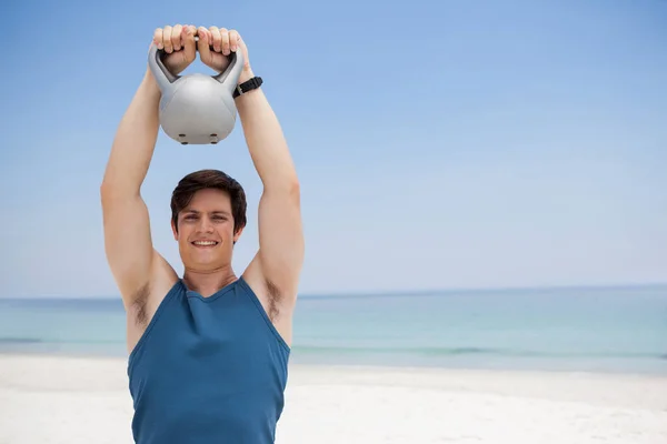 Hombre levantando kettlebell en la playa —  Fotos de Stock