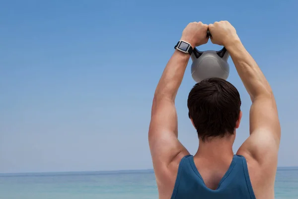 Uomo sollevamento kettlebell in spiaggia — Foto Stock