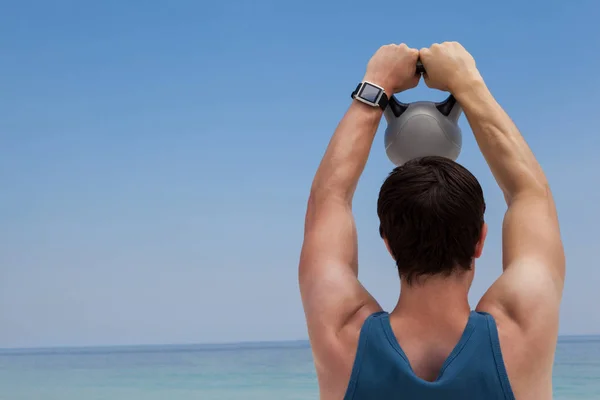 De hijs kettlebell man op strand — Stockfoto