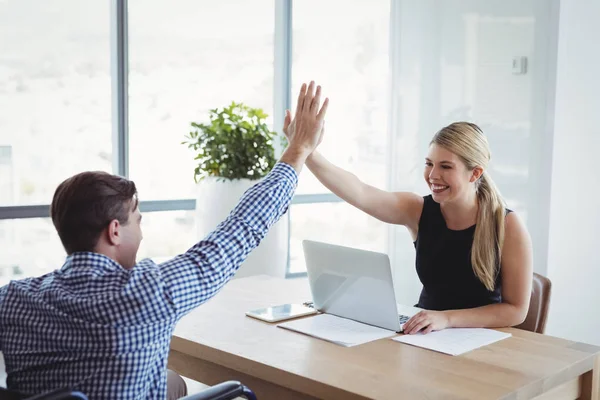 Befattningshavare som ger high-five till varandra på skrivbord — Stockfoto