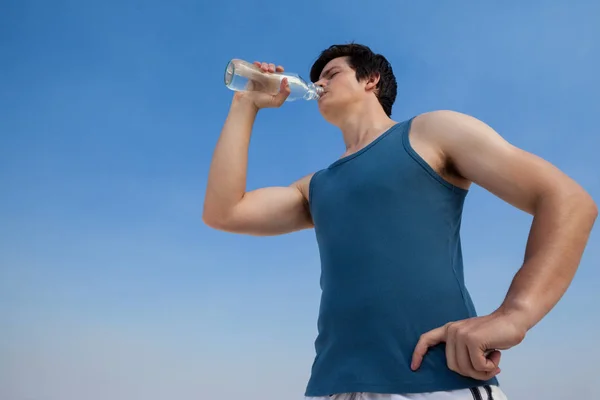 Człowiek woda pitna z butelki na plaży — Zdjęcie stockowe