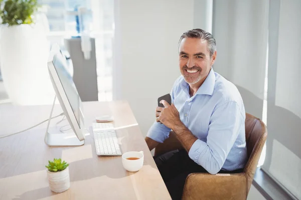 Sorrindo executivo sentado na mesa — Fotografia de Stock