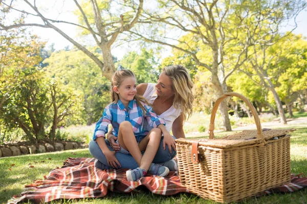 Daughter sitting on mothers lap while having picnic — Stock Photo, Image