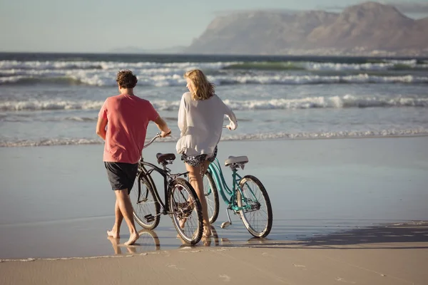 Пара с велосипедами на пляже — стоковое фото