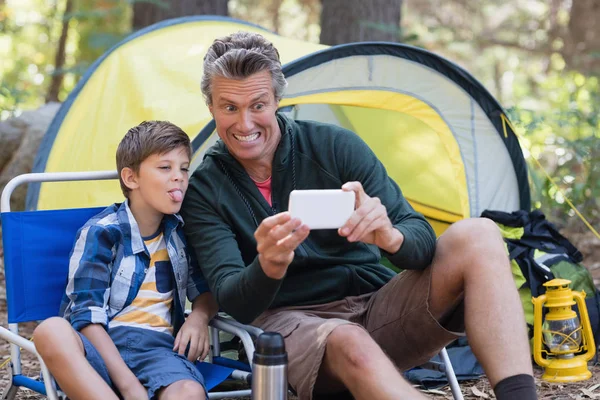 Father and son taking picture by tent — Stock Photo, Image