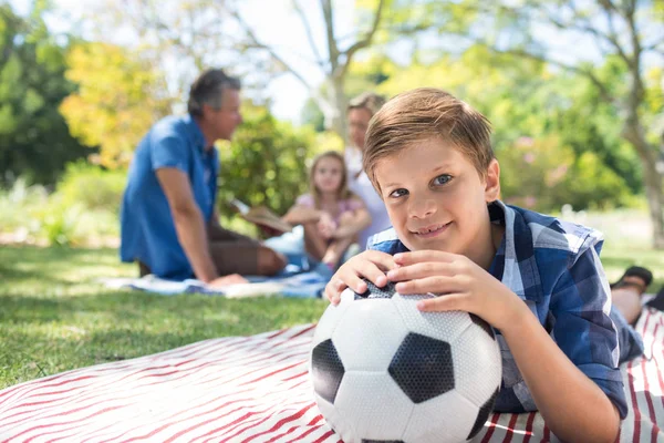 Мальчик опирается на свой футбол на пикнике в парке — стоковое фото