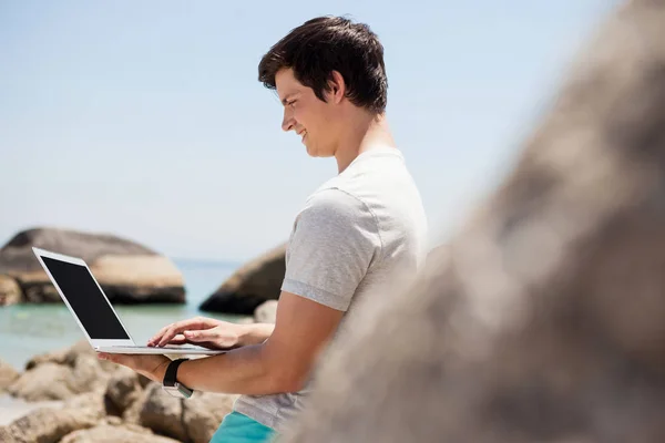 Homem apoiado nas rochas e usando laptop — Fotografia de Stock