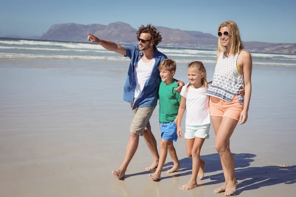 Lycklig man pekar bort med familjen promenader på stranden — Stockfoto