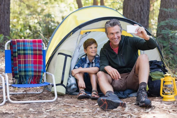 Father and son taking selfie in tent — Stock Photo, Image