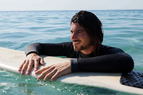 Surfer, opierając się na deski surfingowej w morze — Zdjęcie stockowe